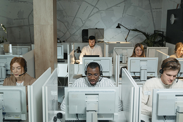 Image of diverse workers in front of computer in a call center in cubicles.