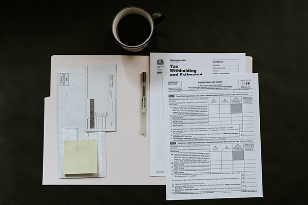 Tax witholding forms on desk in folder with coffee cup
